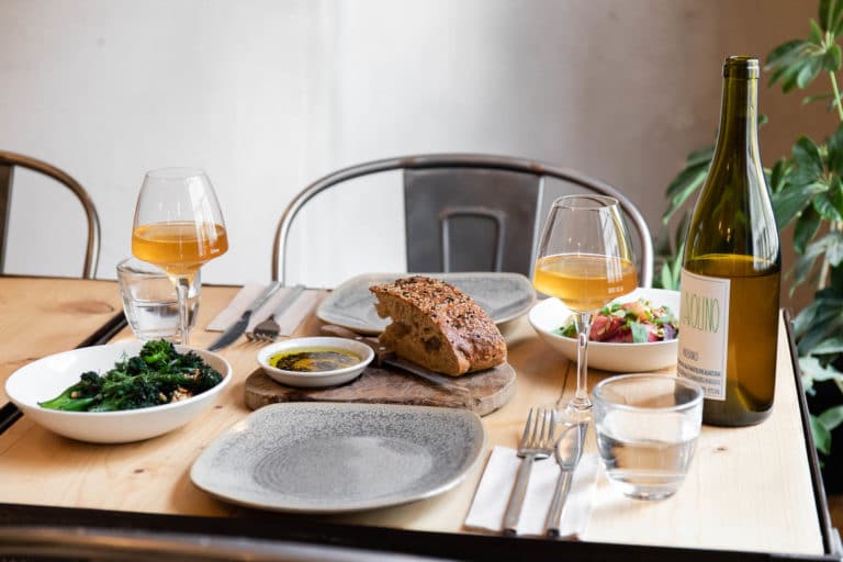 Table set for two, broccoli and salad on the side, two glasses filled with white wine