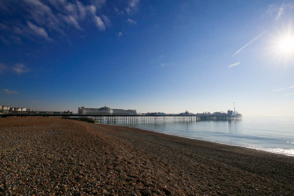 The pebbles, the pier, the sea on Brighton seafront. Very blue sky