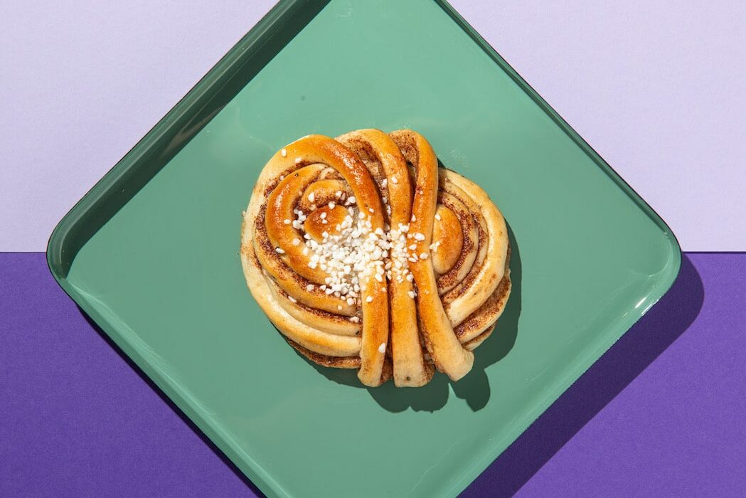 Cinnamon buns from Fika Bakery in Brighton. Presented on a green plate with a purple background.