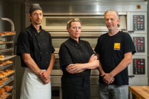 What is Fika? Fika Ltd in Brighton. Pictured - head baker Pawel Cichowski with directors Jenny Engvall Viv Craske. In an industrial looking kitchen