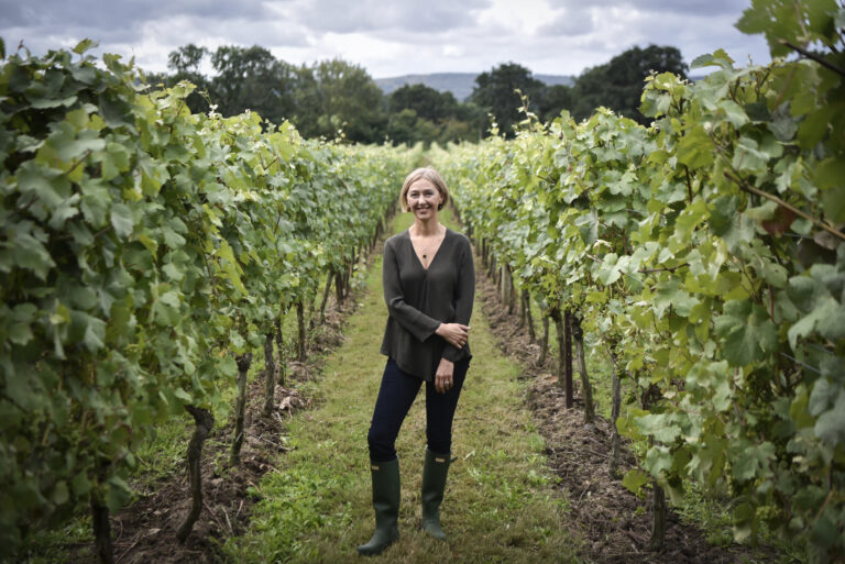 Cherie Spriggs, Head Winemaker at Nyetimber, standing among vineyard vines in Sussex