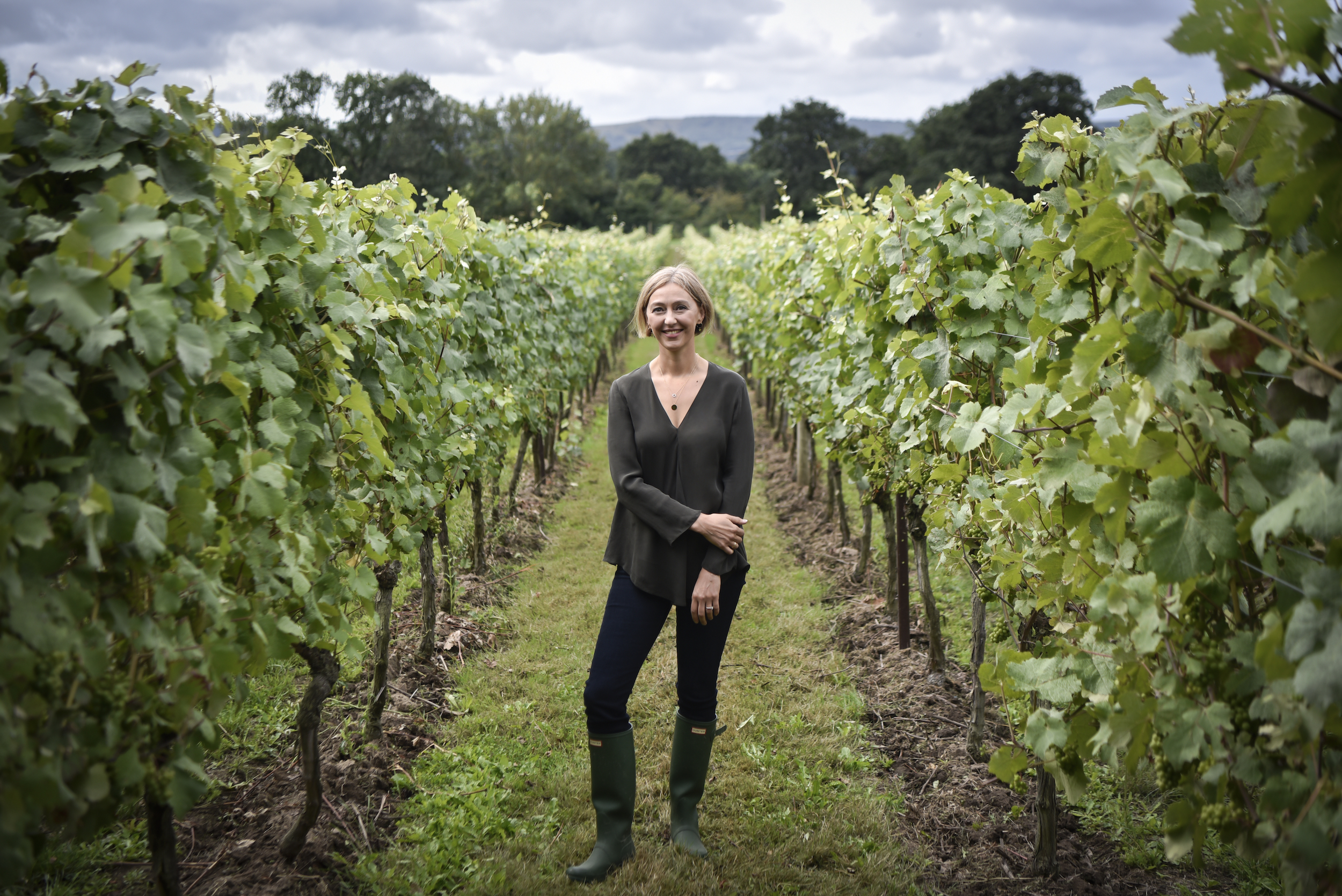 Woman smiling between rows of vines in a vineyard