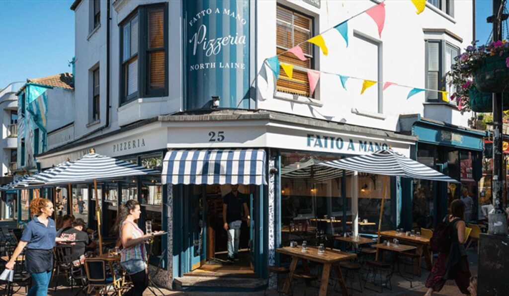 Exterior photo of pizzeria in Brighton on a sunny day.