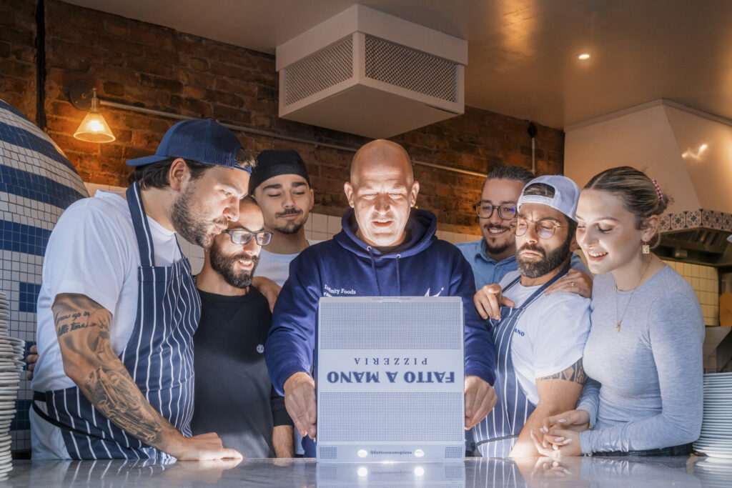 A group photo of the team at pizzeria Fatto a Mano all looking into a pizza box.