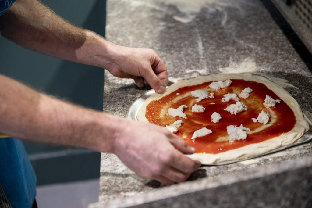 Fresh pizza being made with a tomato sauce and cheese about to be put in the oven.