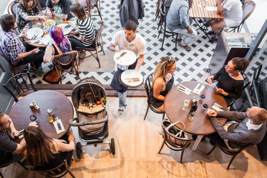 A busy restaurant, overhead shot, with people eating and people serving food.
