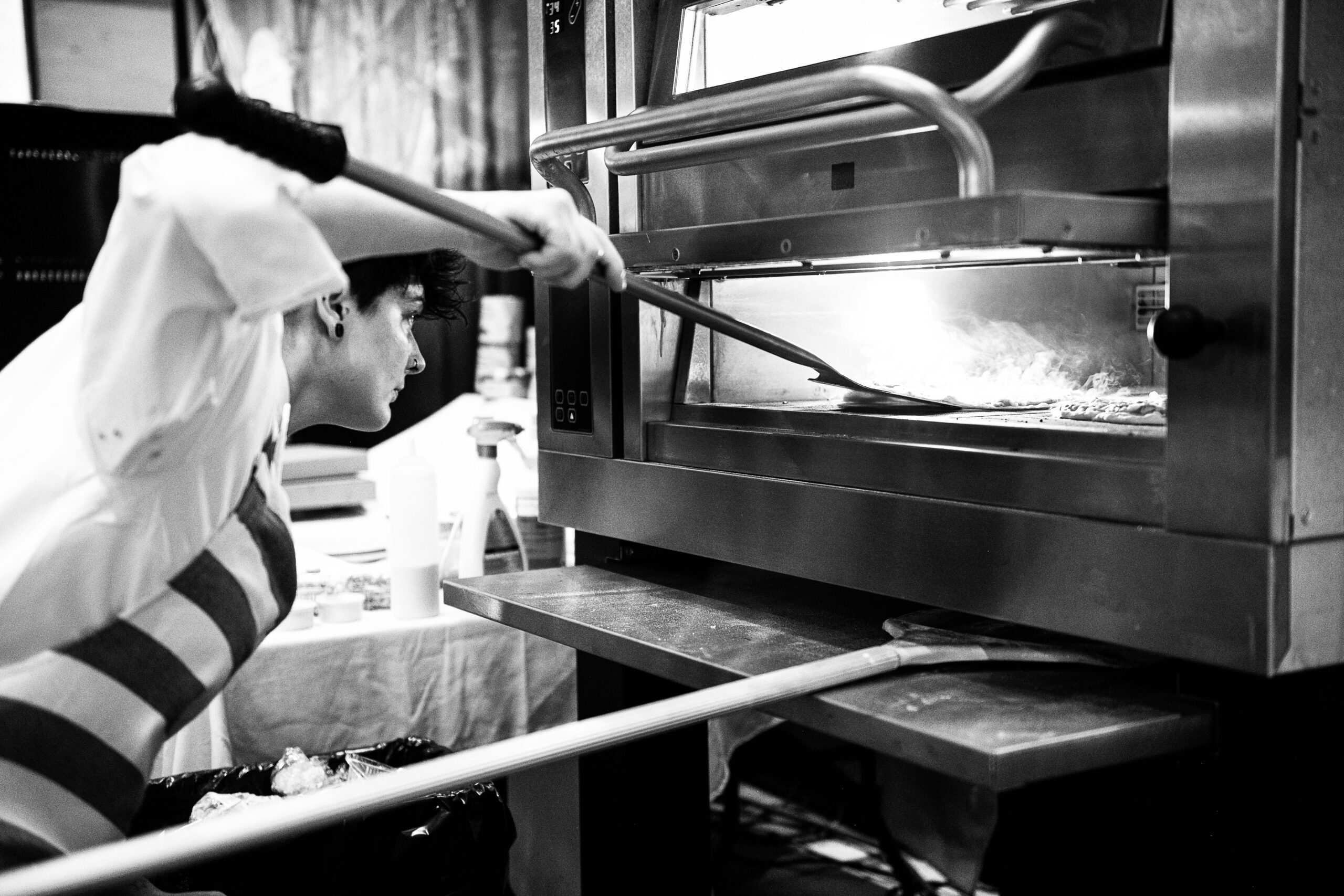 Brigi Stamber - Bkack and White Picture - putting pizza in pizza oven