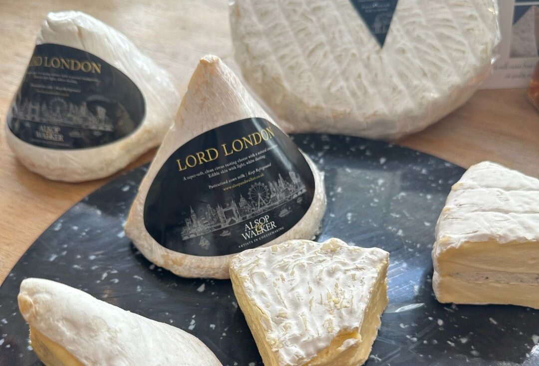 Alsop and Walker Lord London cheese, made in Sussex. Alsop and Walker Lord London soft cheese, a cone shaped cows milk cheese with a white rind, displayed with wedges of Sussex soft cheeses on a black marble board.