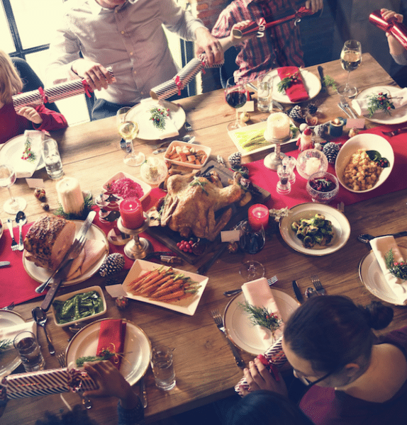 Christmas table with lot of food and people pulling Xmas crackers
