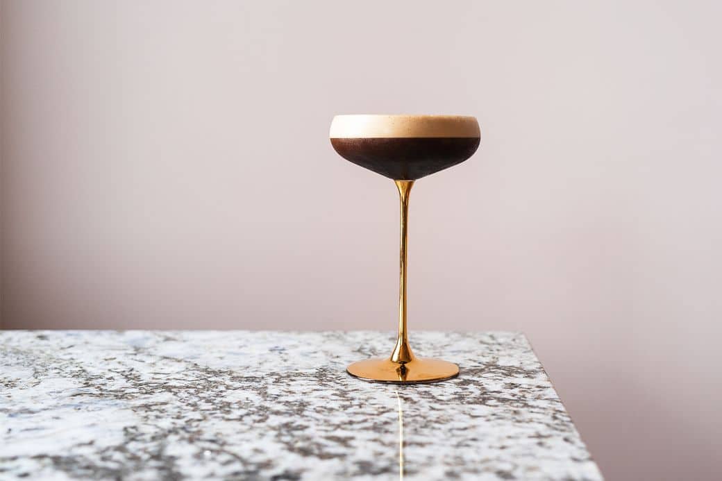 espresso martini in the golden cocktail glass left on the granite looking table