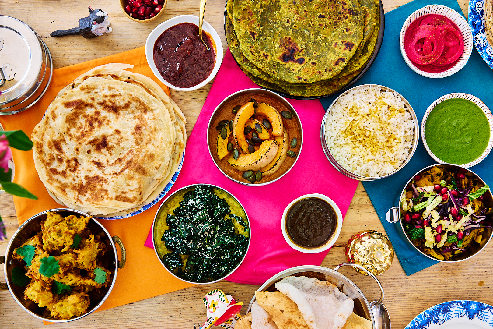 A colourful Indian feast on a wooden table shot overhead. Indian delivery service in Brighton