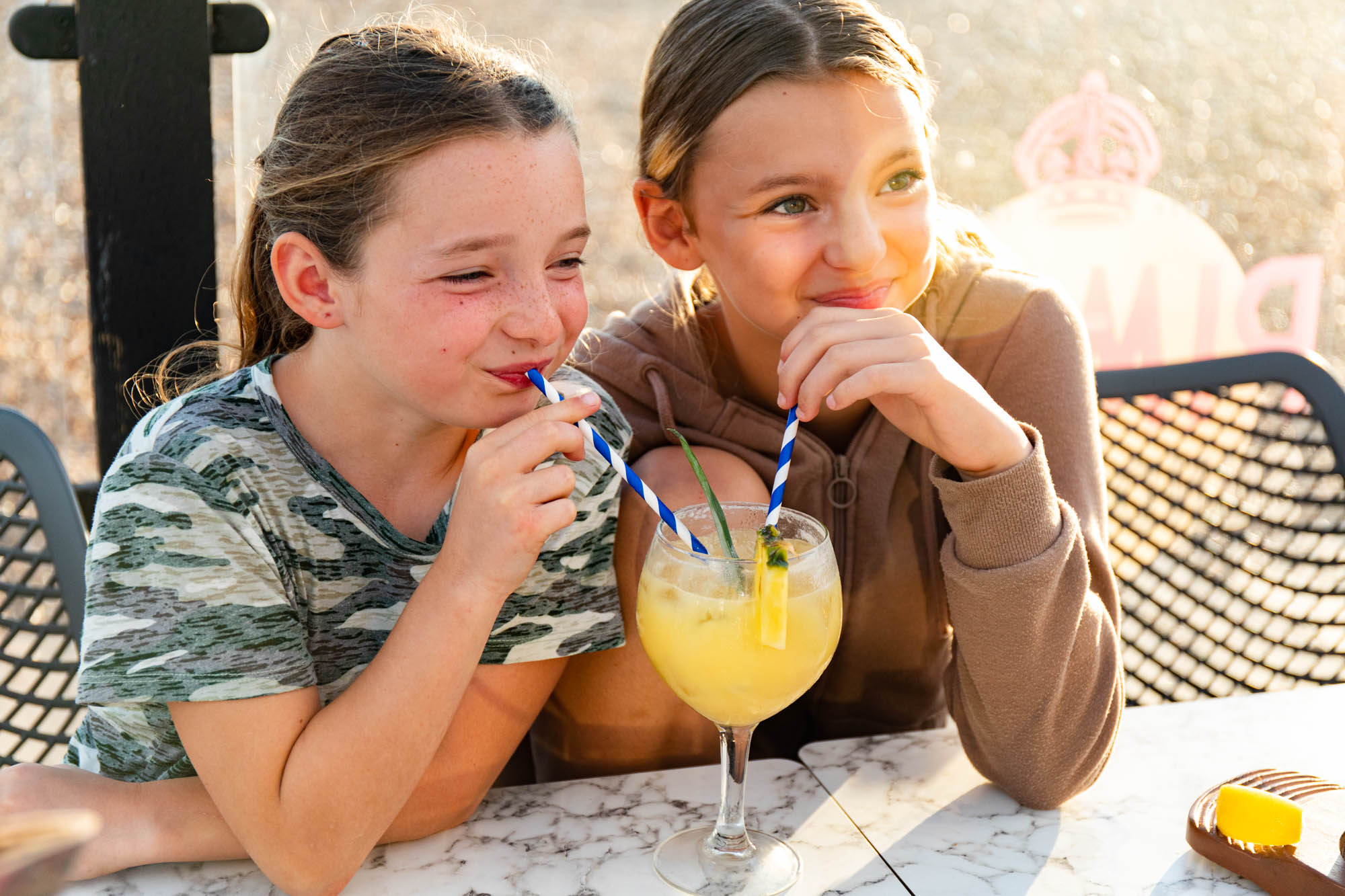 Shot of two girls sharing orange juice at Ohso