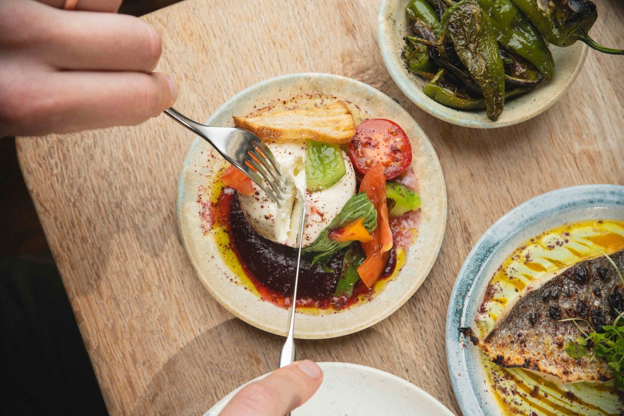 overhead shot of person cutting through mozzarela on the plate