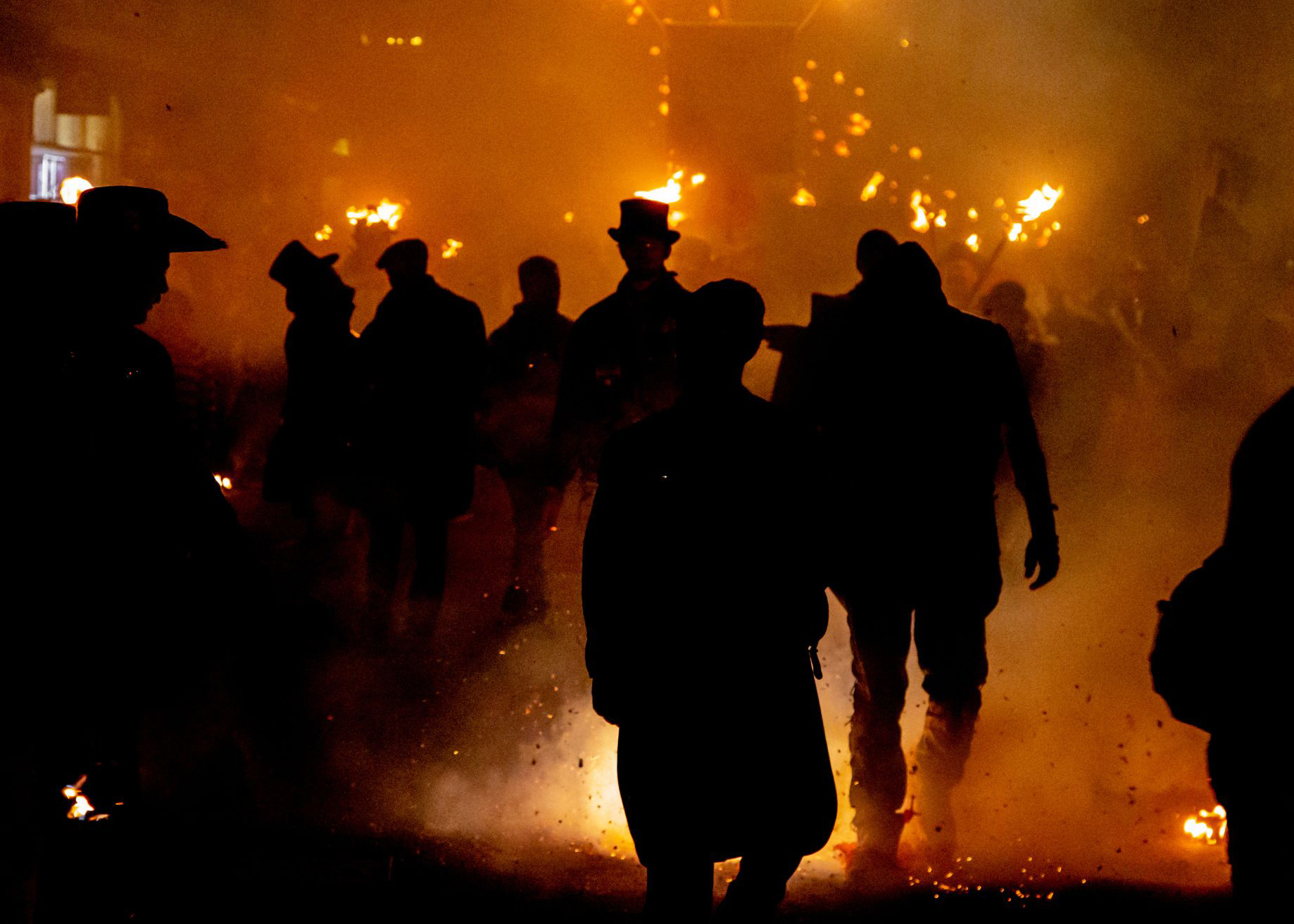 Silhouettes of people against the orange light of fire