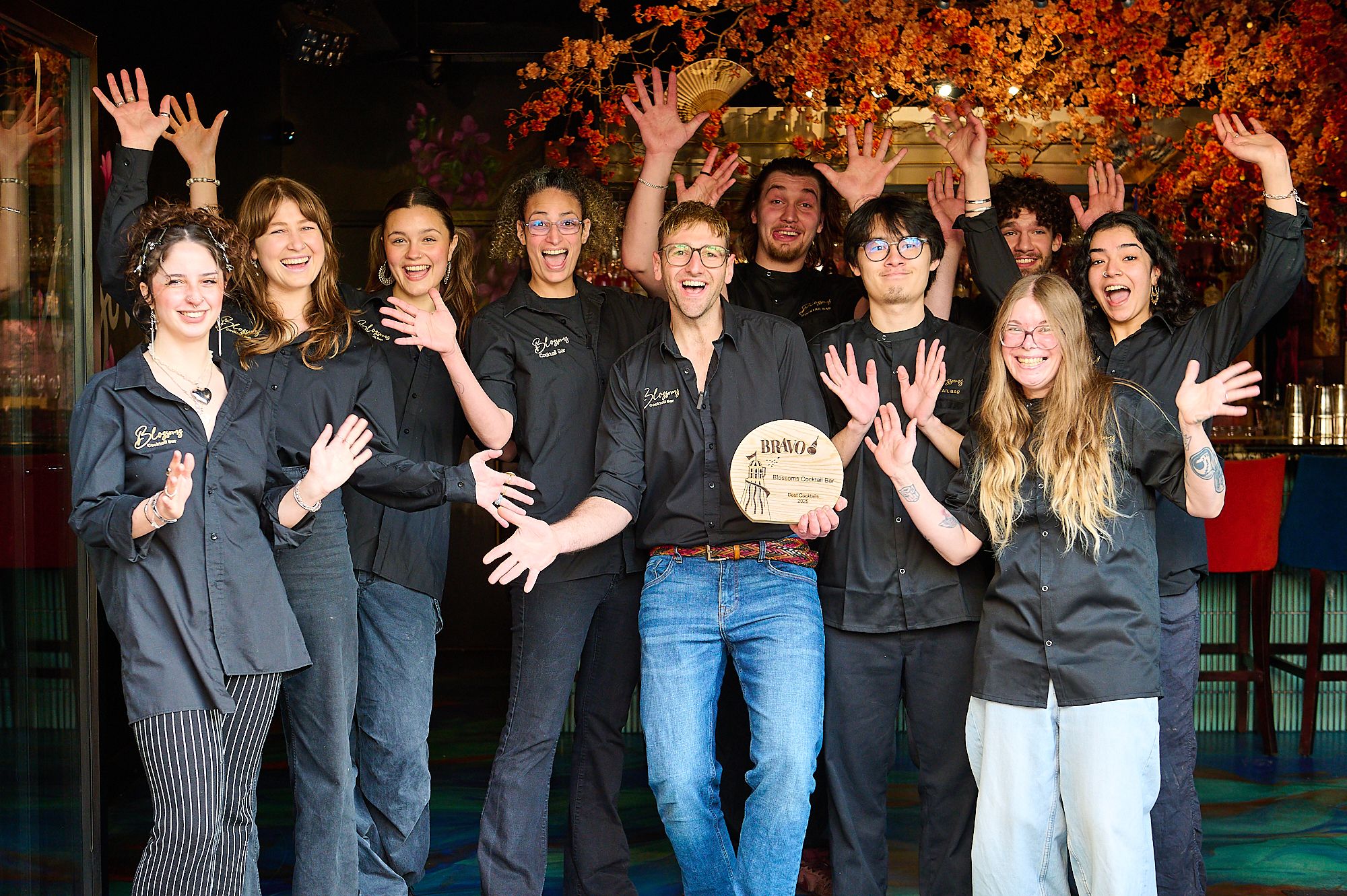 a team of men and women in black shirts celebrating a trophy