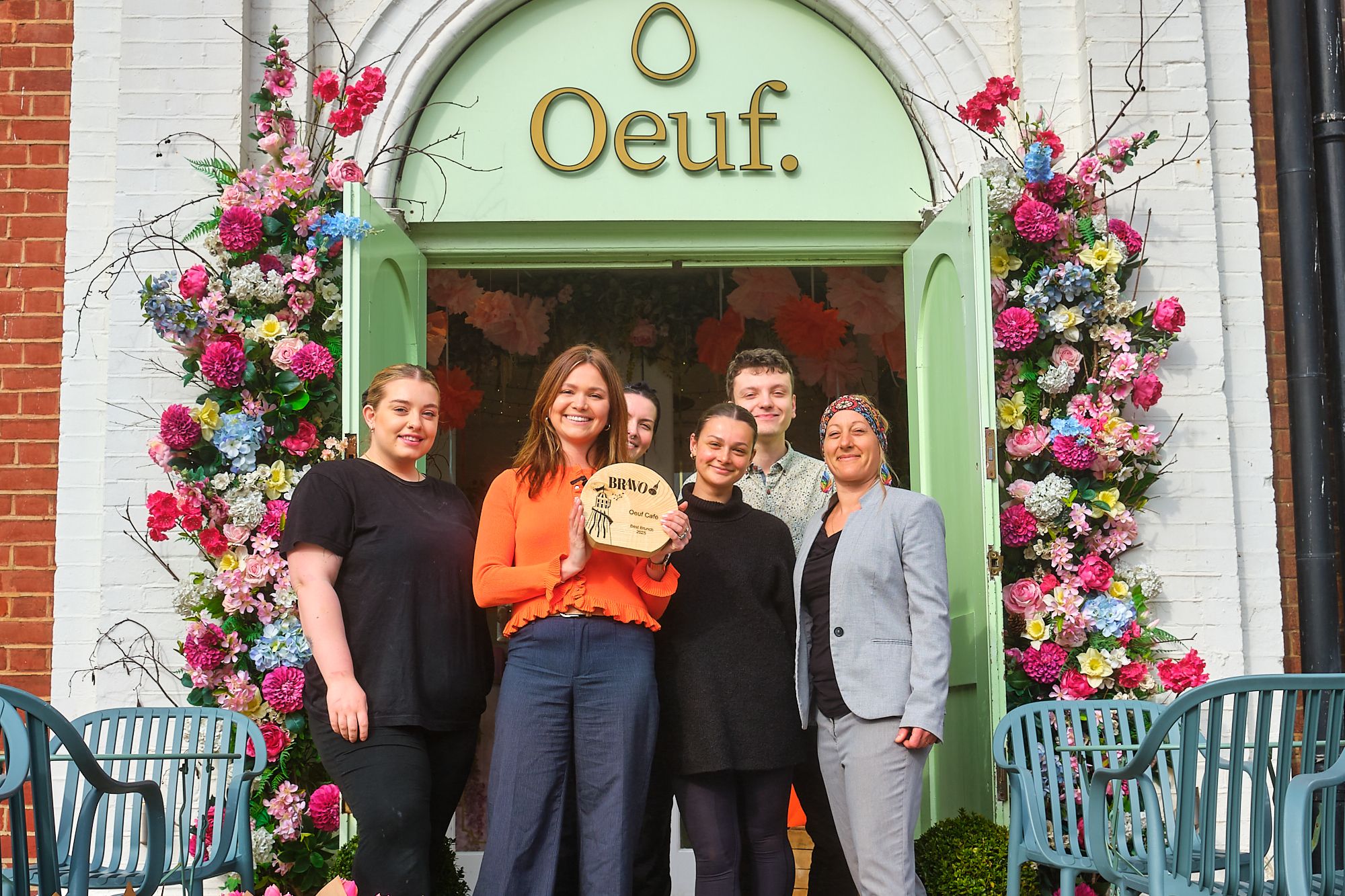 Oeuf team in front of the venue celebrating their BRAVO win and holding the trophy. Oeuf won the best brunch accolade in Brighton for 2025. They are a multi award winner of best brunch in Brighton.