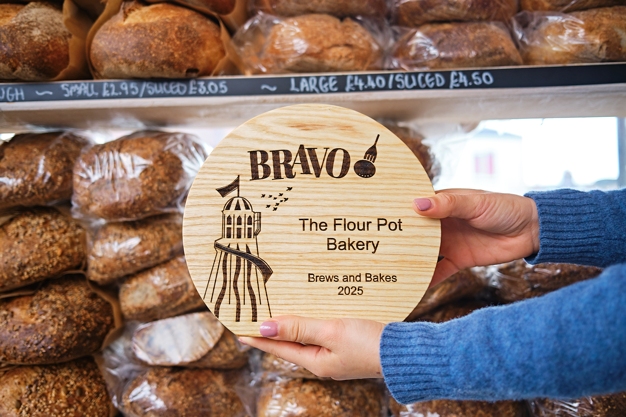 The Flour Pot Bakery BRAVO 2025 trophy being held in front of the breads