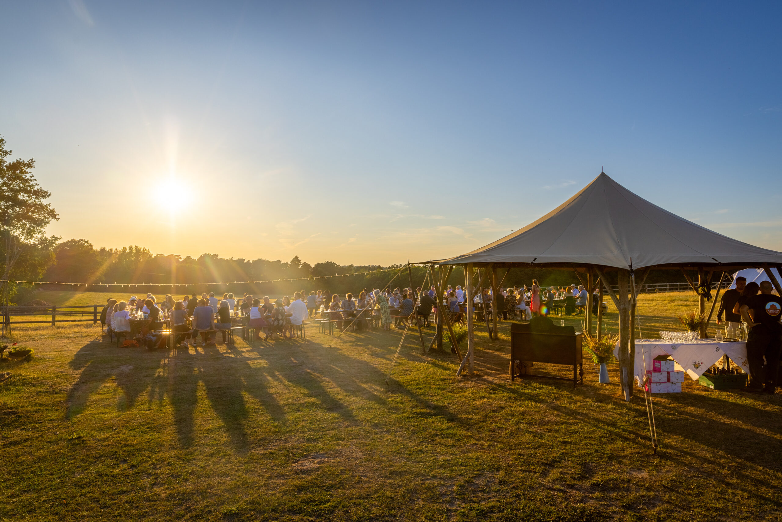 Woodfire event, sunset and people enjoying food and drink on the campsite