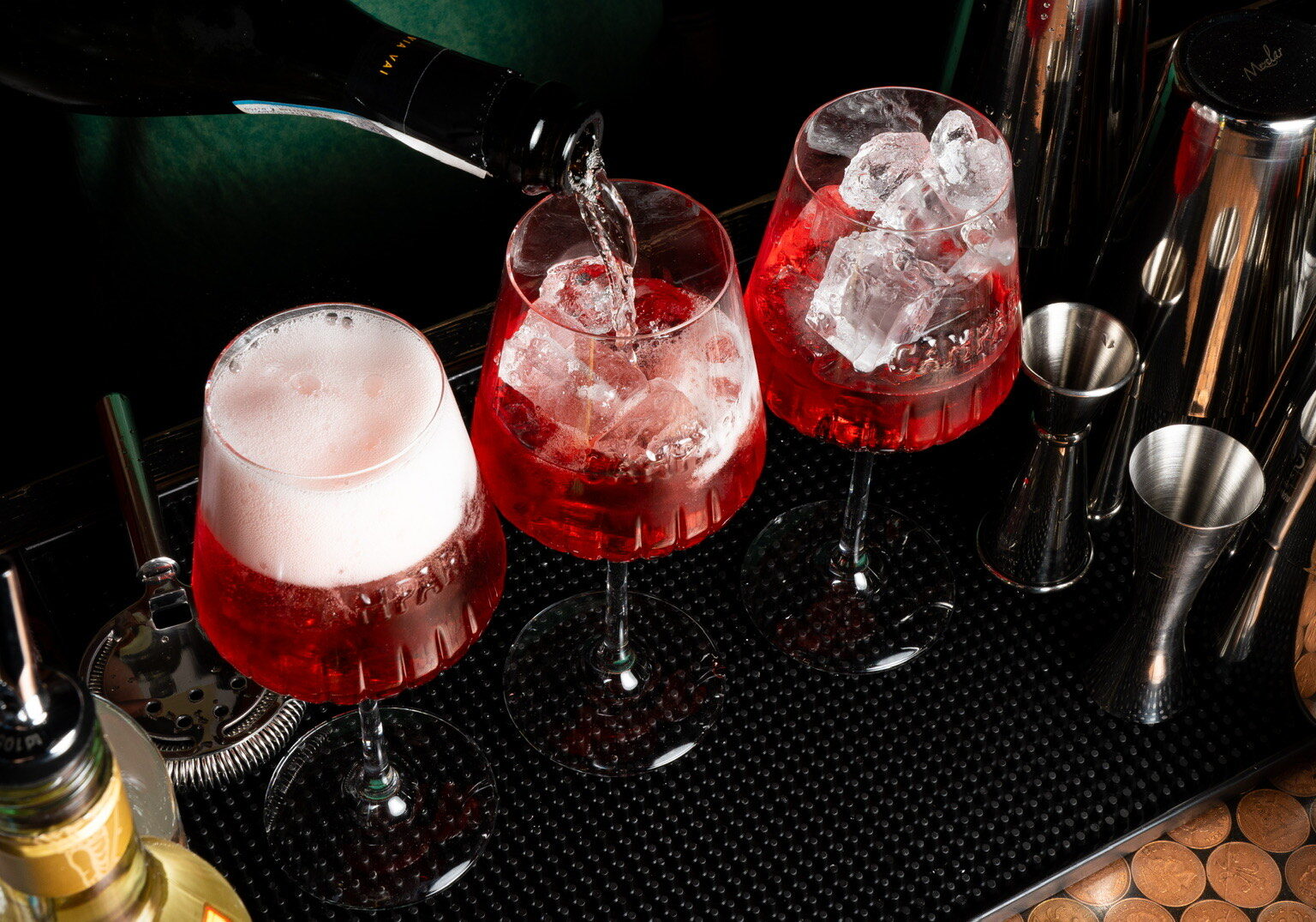 Three glasses of red liquid on a bar