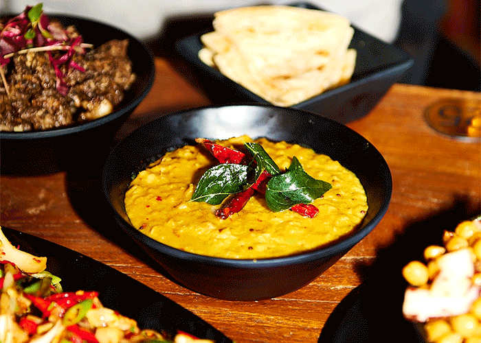 yellow curry being spooned out of a black bowl