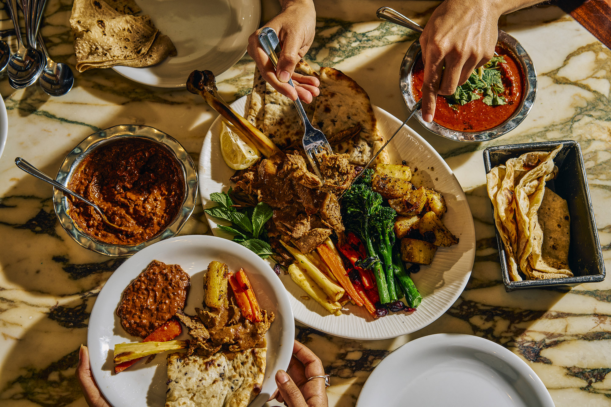 Overhead photo of a festive feast with lots of food and people tucking in.