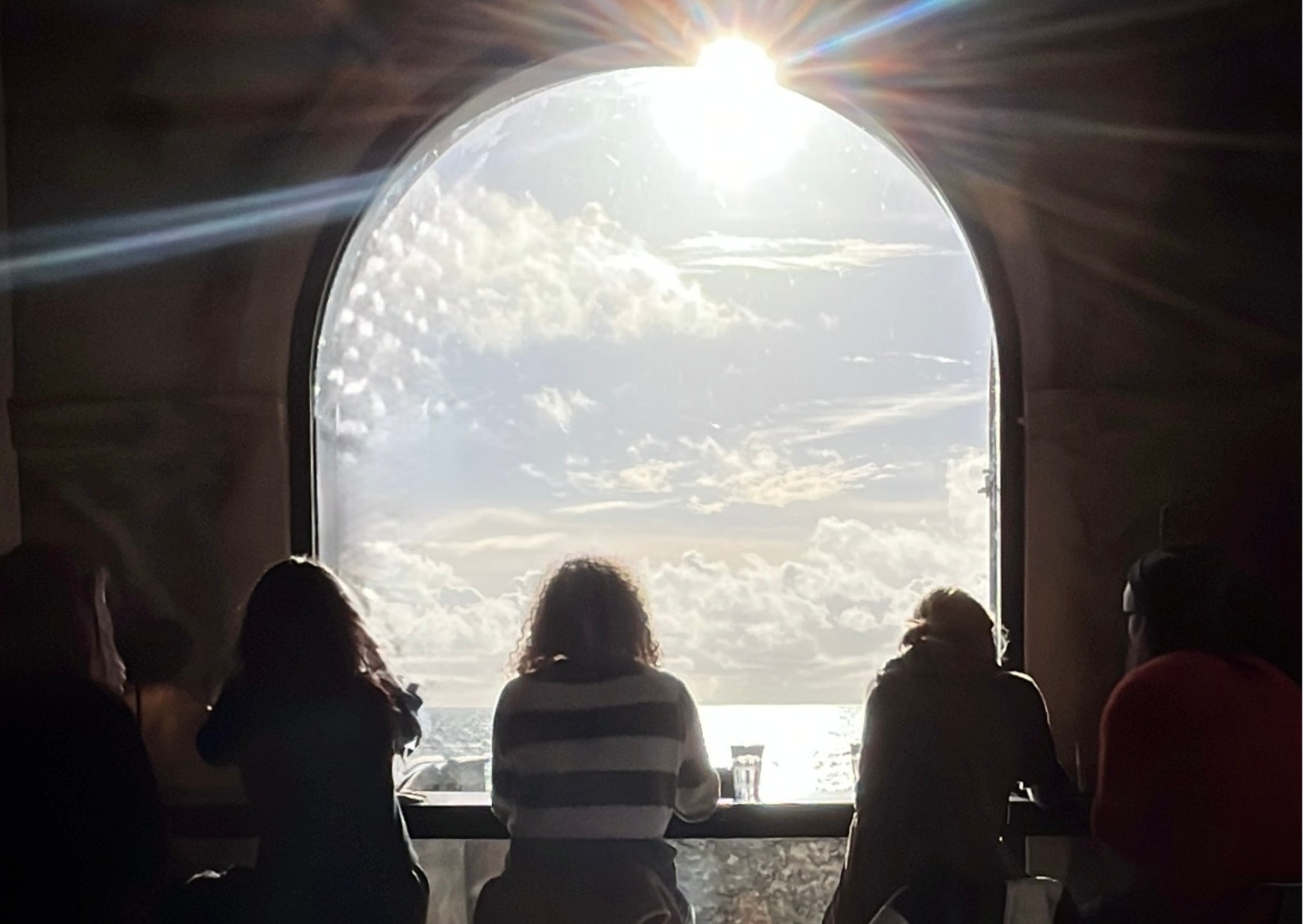 People sitting in a window facing the sun