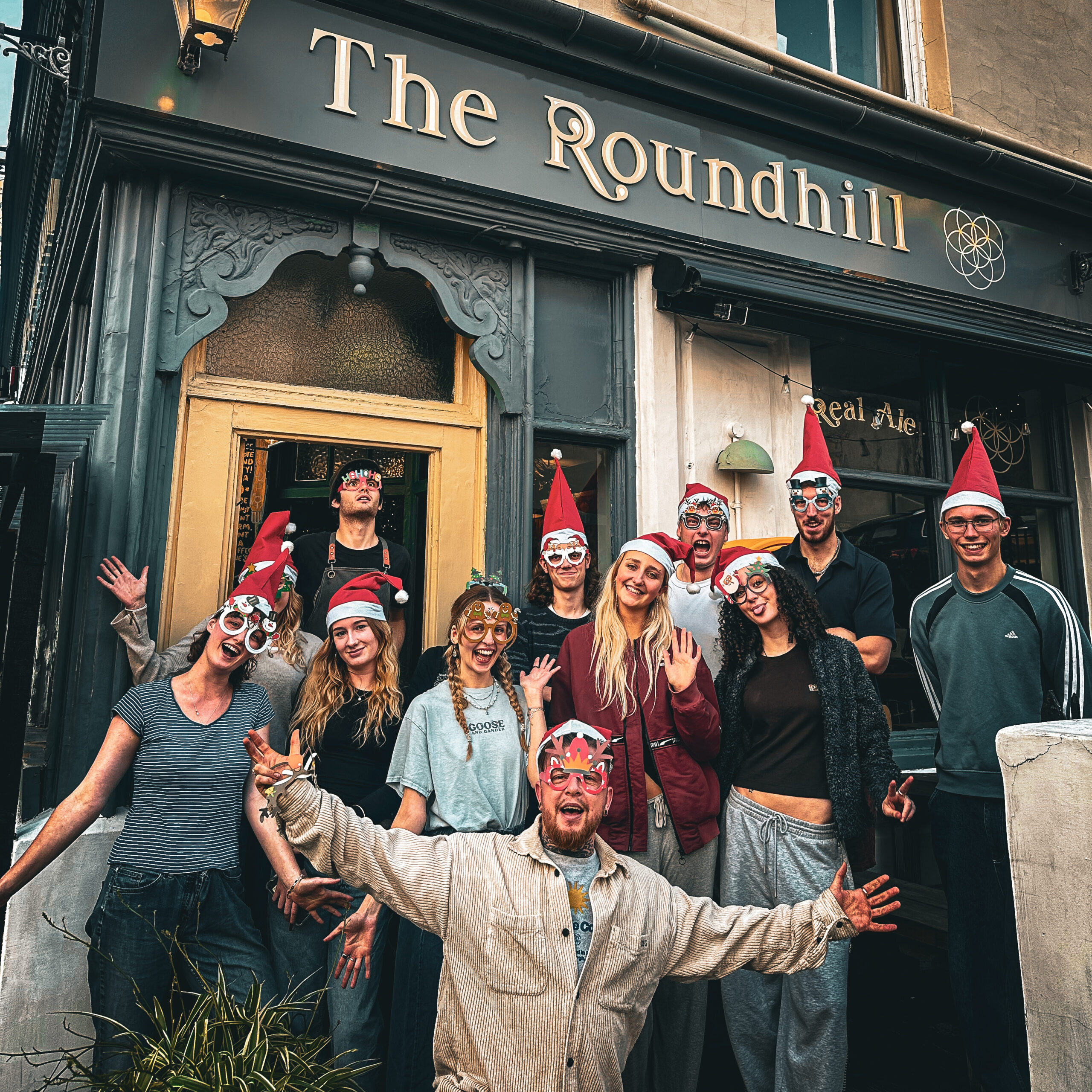 Happy people in santa hats in from of the roundhill pub