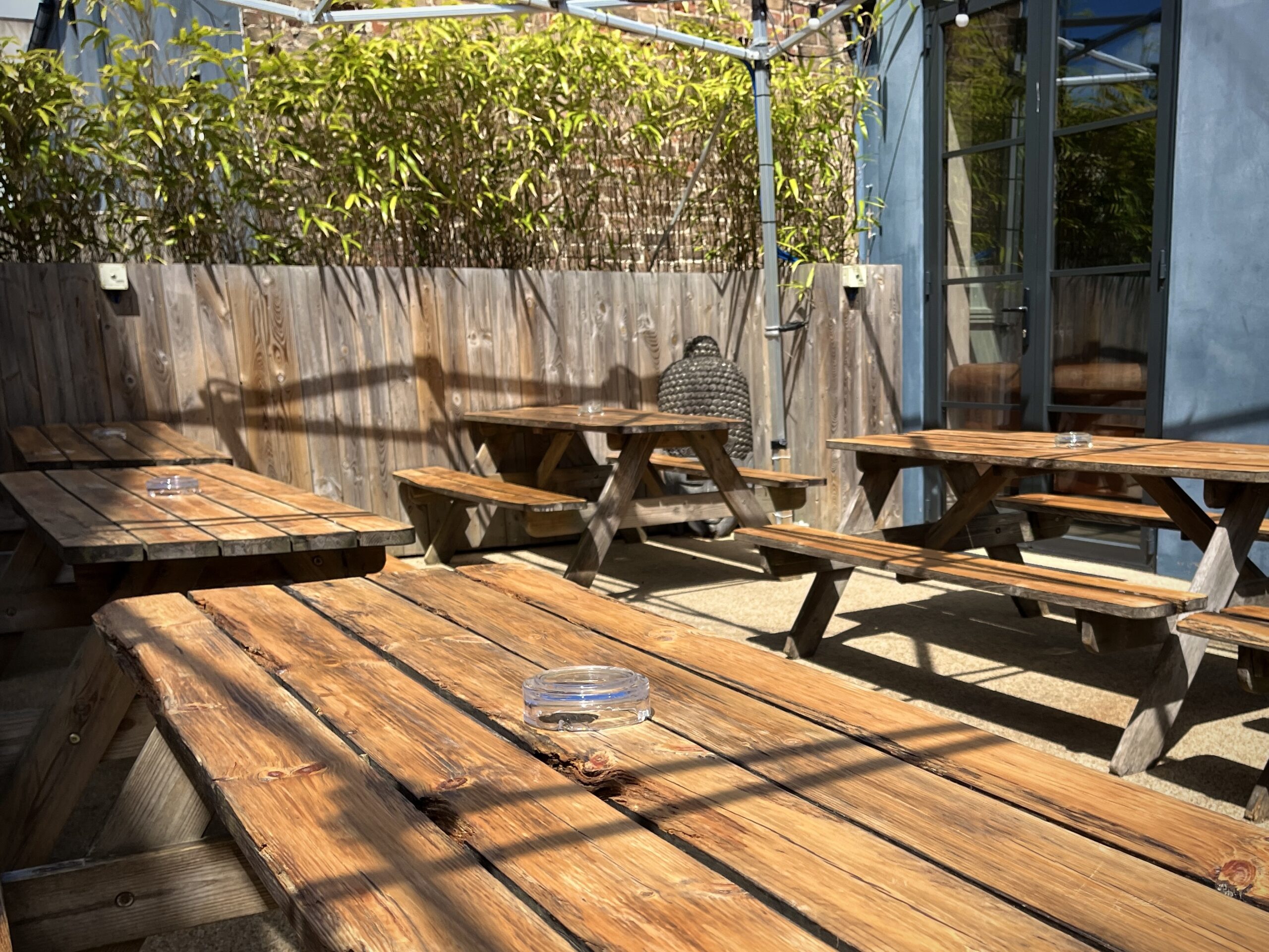 a sun drenched beer garden with bench seating. 